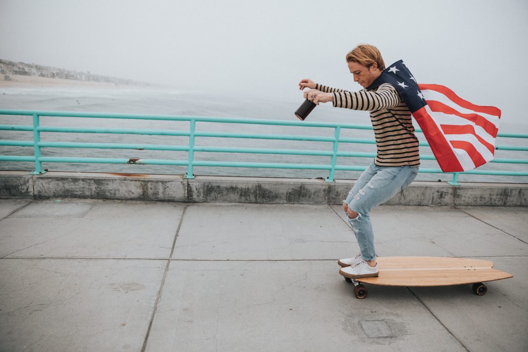 boy skateboarding with American flag cape