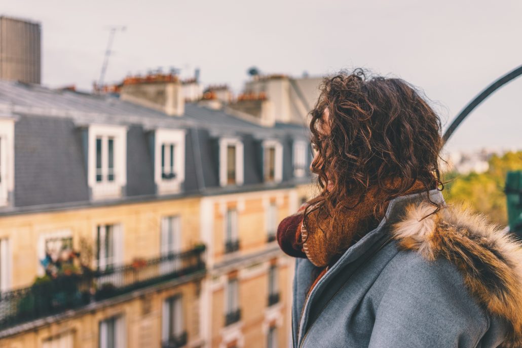 Woman looking out from balcony in Paris