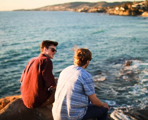 Two men having a conversation near the ocean
