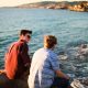 Two men having a conversation near the ocean