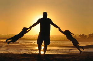 dad swinging children on beach