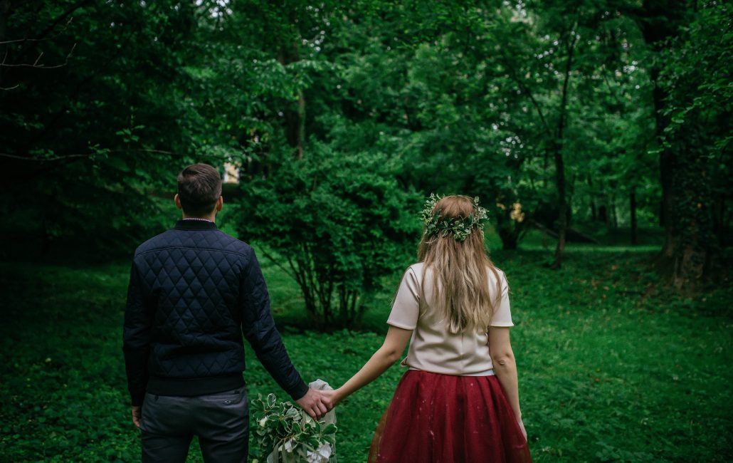 couple holding hands in green space