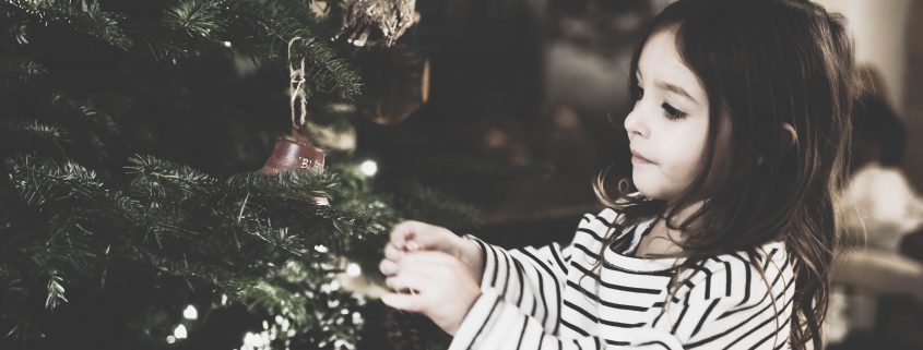 Girl hanging ornaments on tree