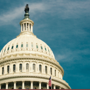 US capitol building against a blue sky with flag