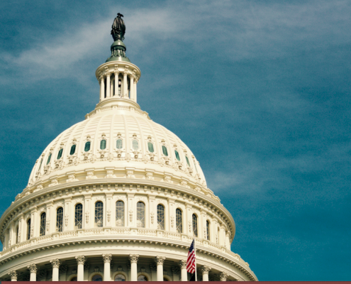 US capitol building against a blue sky with flag