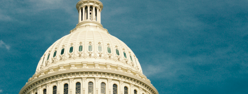 US capitol building against a blue sky with flag