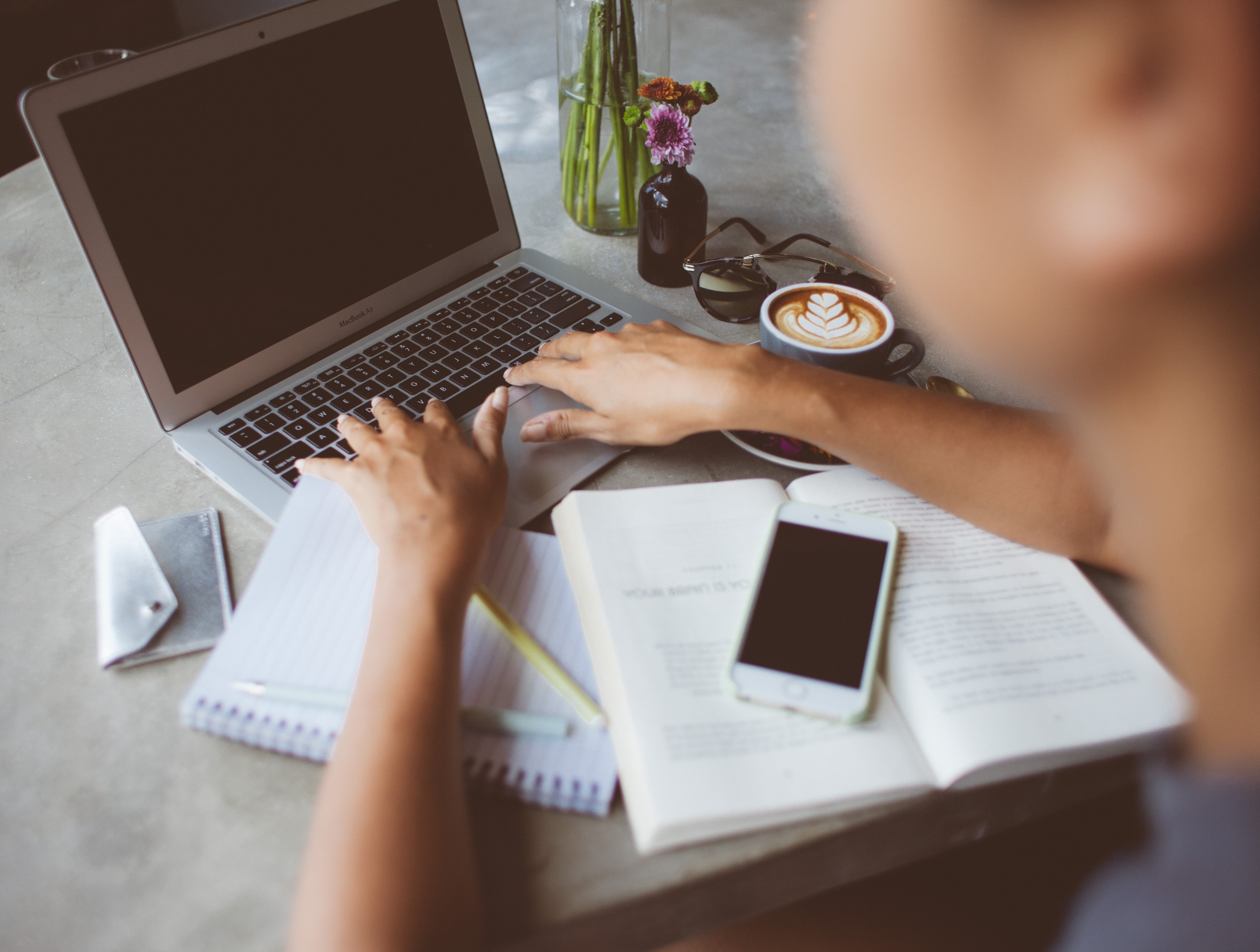 man typing on computer with phone in forefront