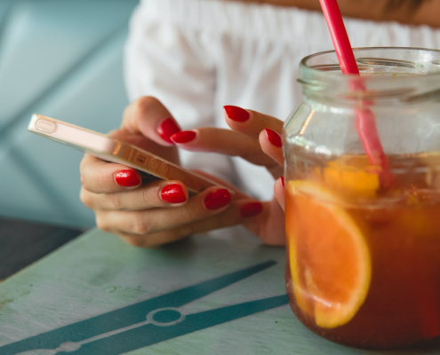 woman reading on phone with red nails