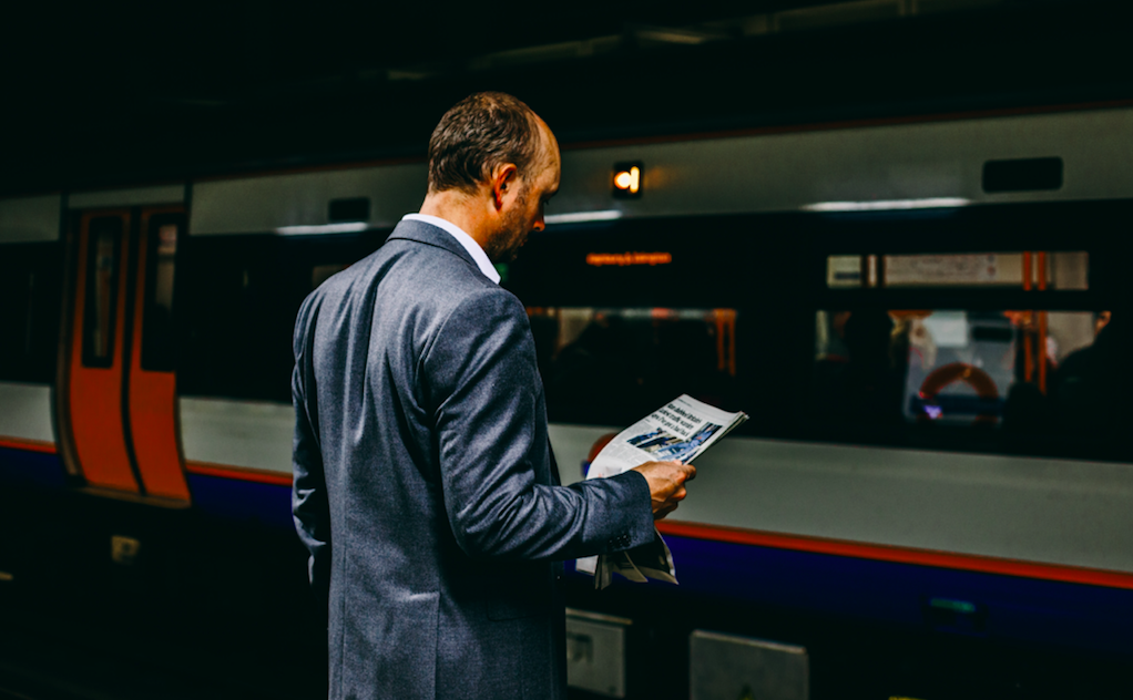 man with newspaper near train