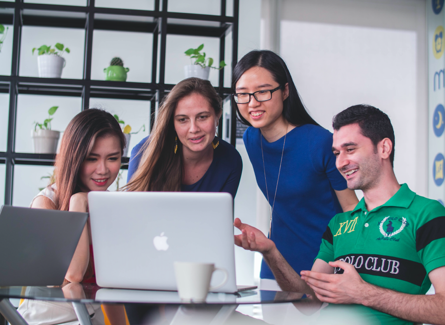 four people around a computer