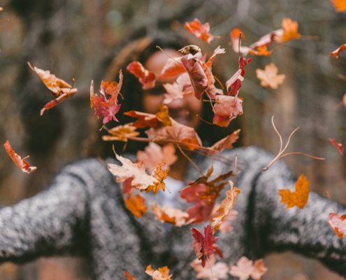 woman tossing leaves in air