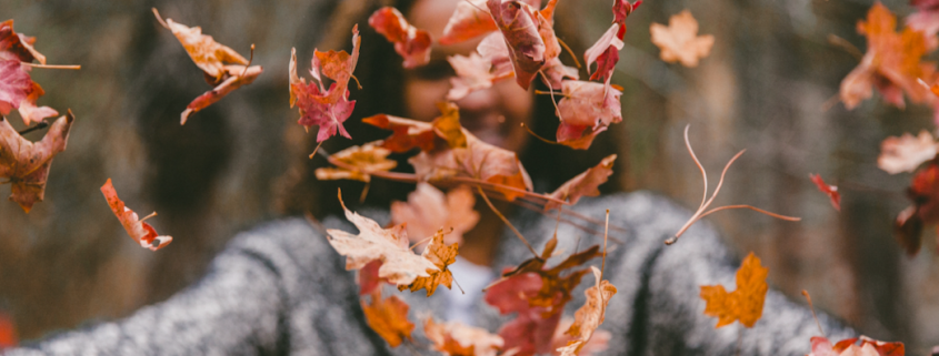 woman tossing leaves in air